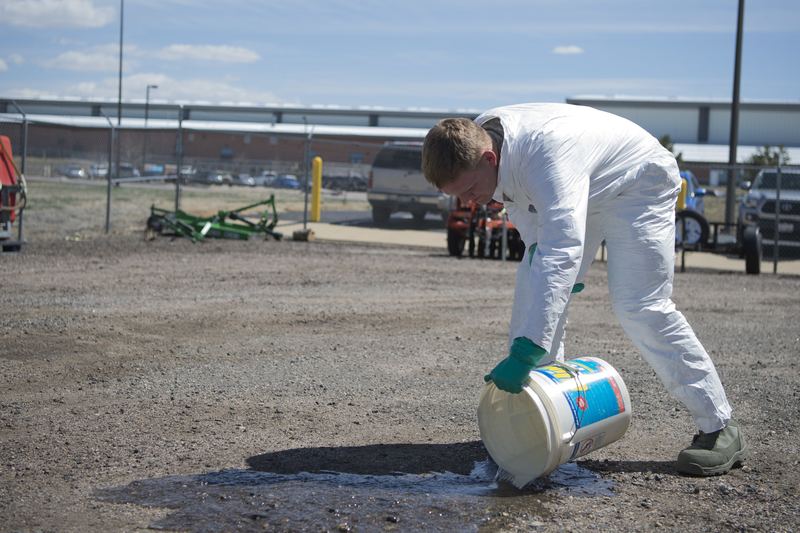 Airman Steven R. Ewell, 460th Civil Engineer pest management apprentice, empties a bucket after thoroughly cleansing his